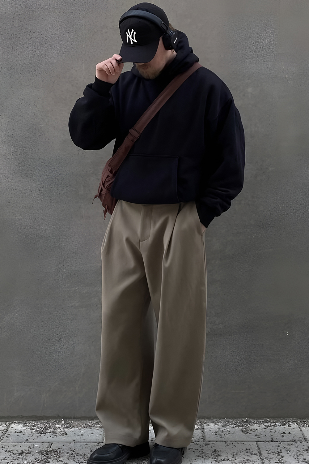 Minimalist streetwear editorial look in dark tones against a neutral background
